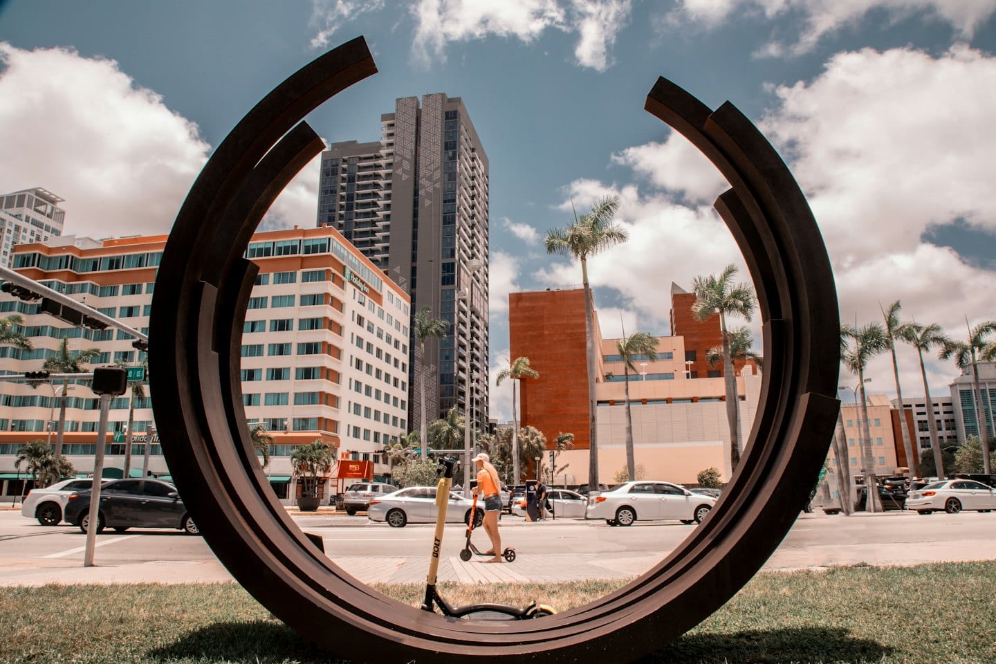 Persona en patinete eléctrico por una calle soleada de la ciudad.