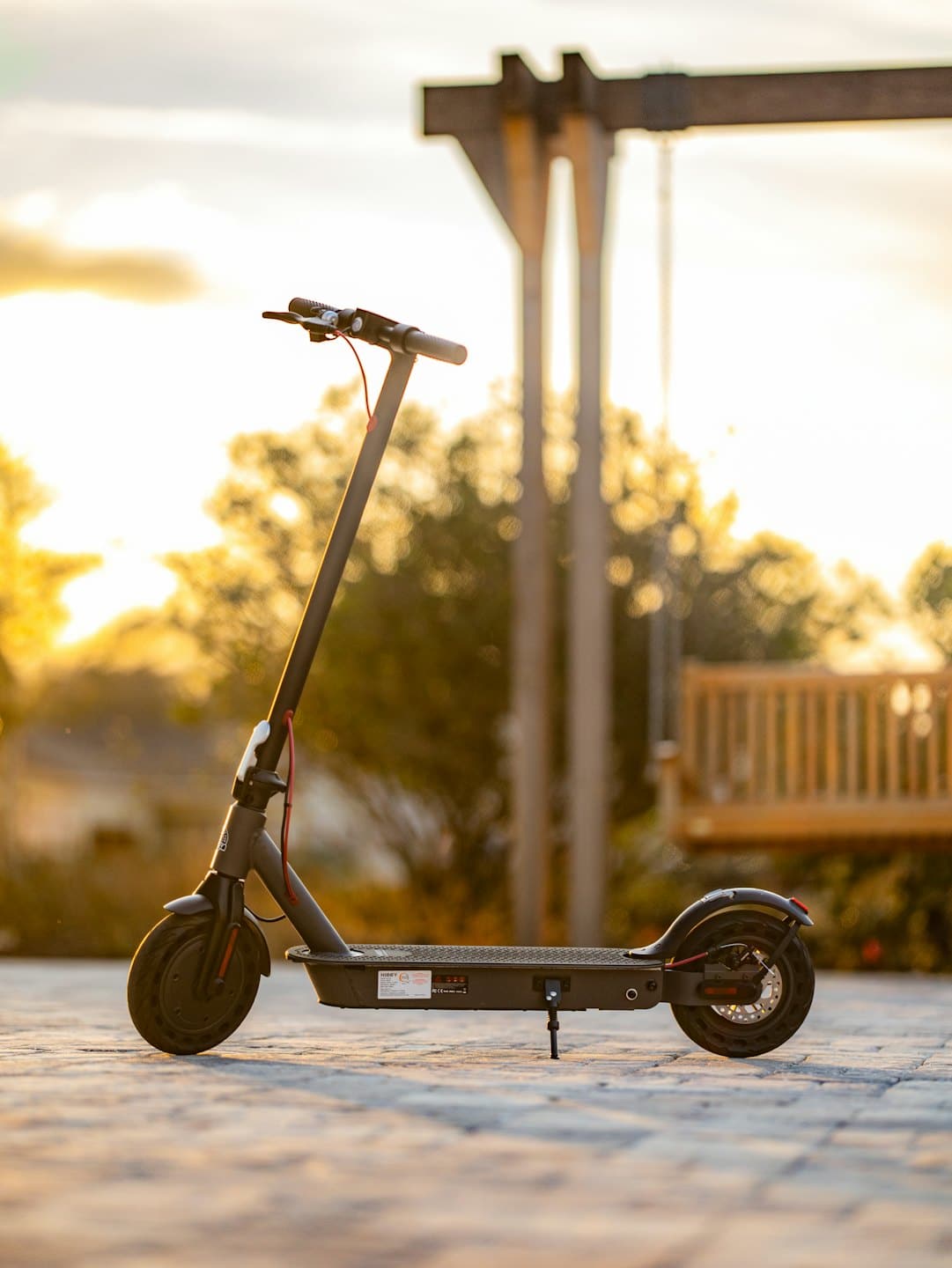 Scooter eléctrico aparcado en una zona pavimentada con la luz del sol de la hora dorada.