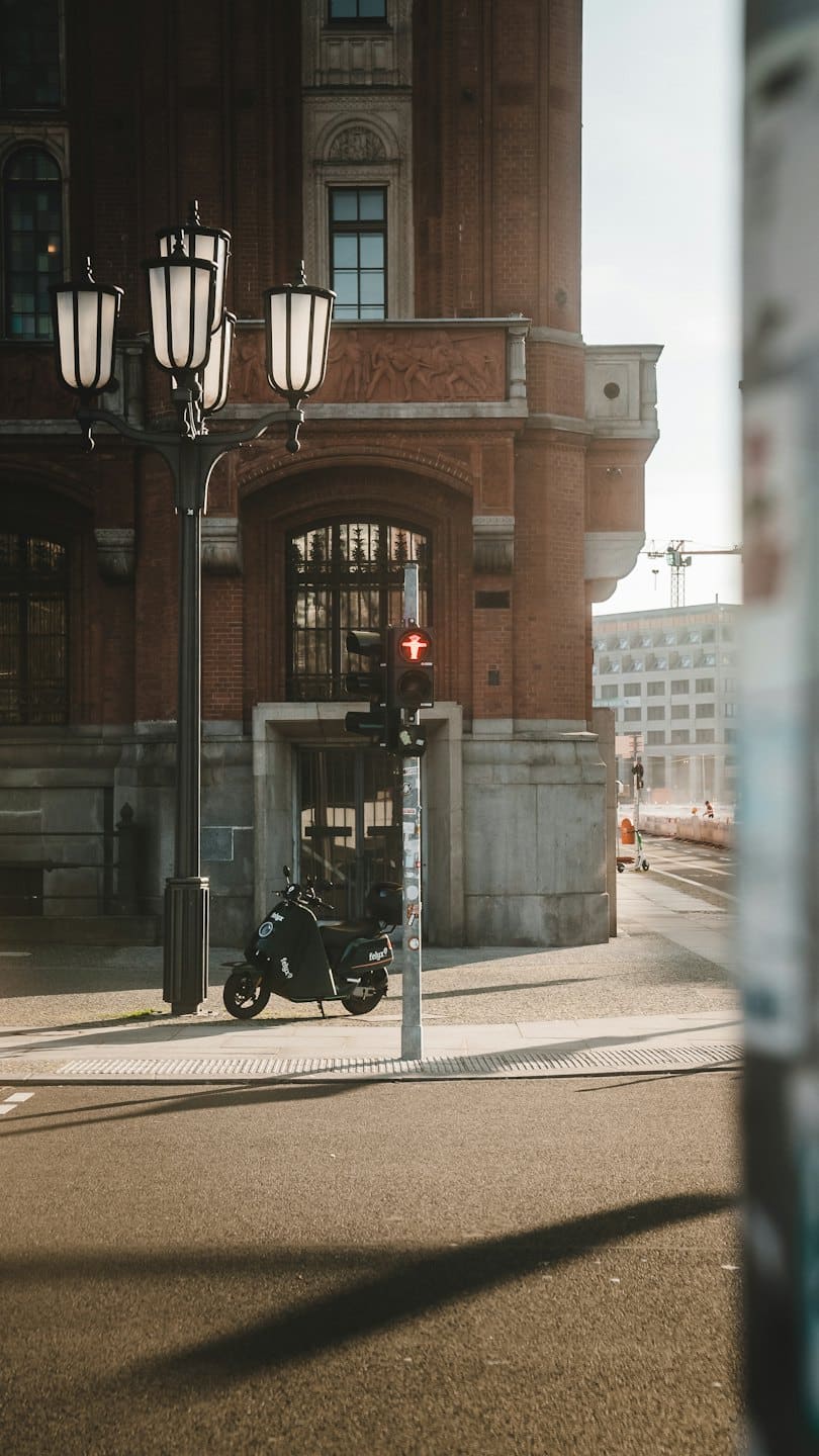 Un patinete eléctrico aparcado en una acera junto a un edificio de ladrillos.
