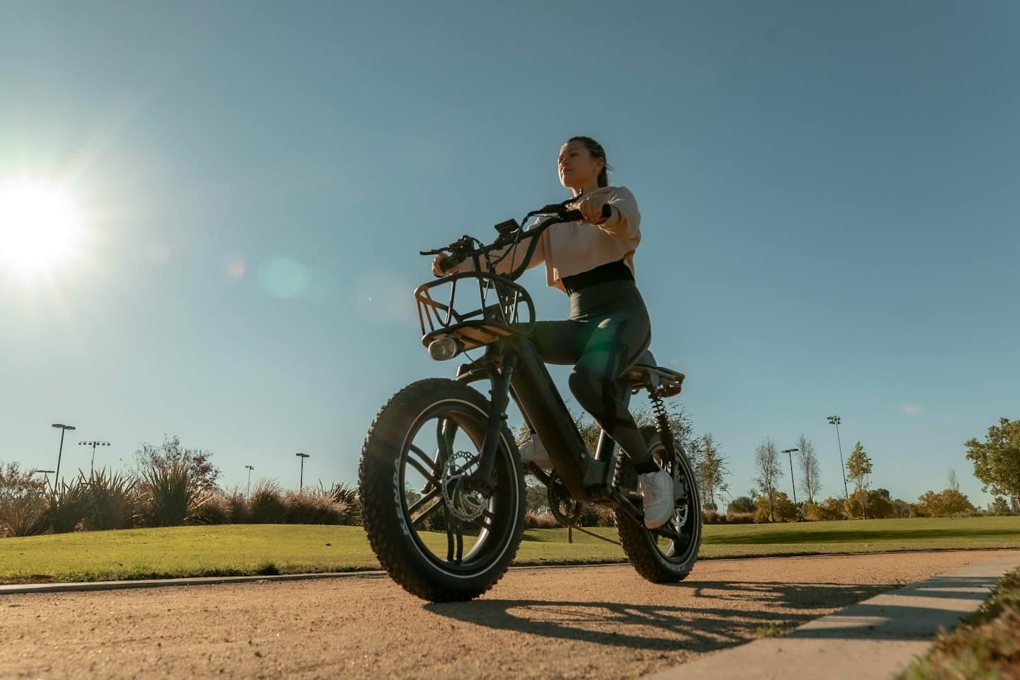 Mujer pasea en bicicleta eléctrica por sendero de parque.