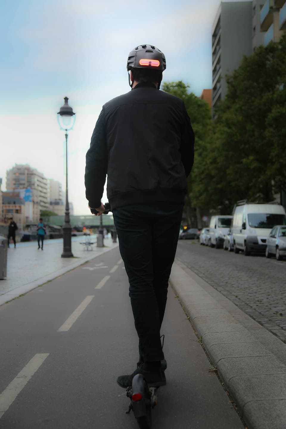 Una persona monta un patinete eléctrico por un carril bici urbano.